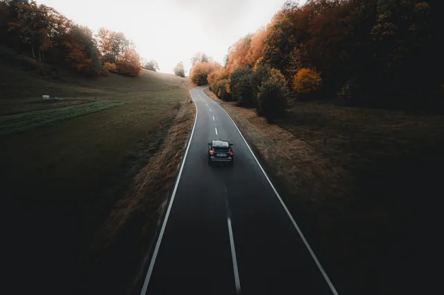 Luftaufnahme einer Straße zwischen Herbstwäldern