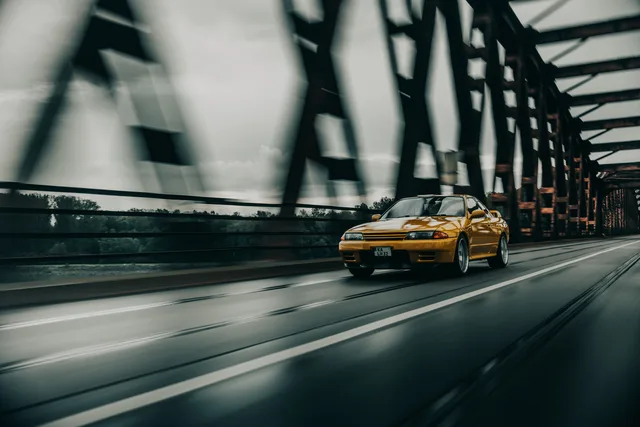 Gelber Nissan Skyline R32 in Fahrt auf einer Stahlbrücke