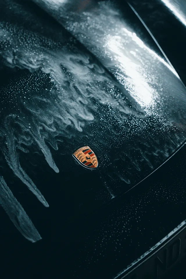 Porsche-Wappen auf nasser Haube